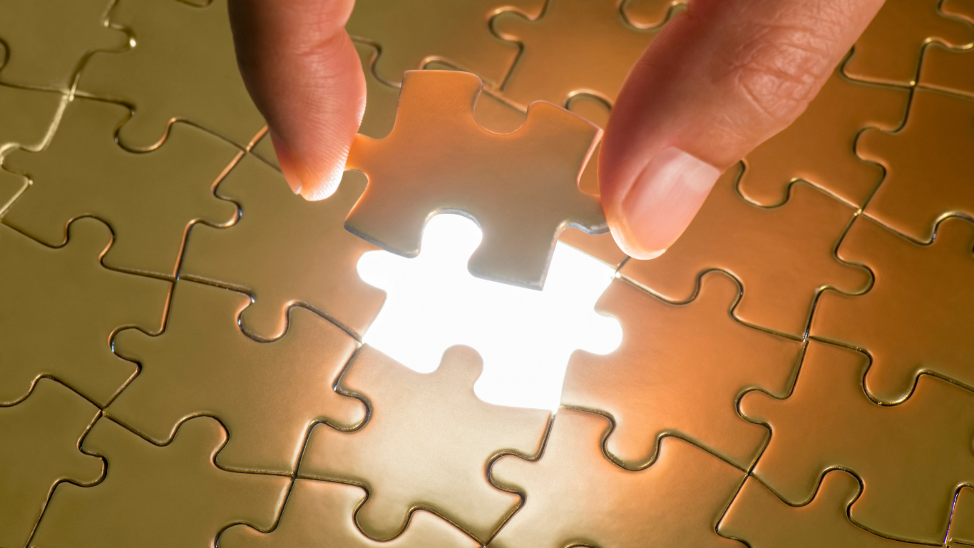 A gold puzzle with a hand placing the last piece in a glowing space.