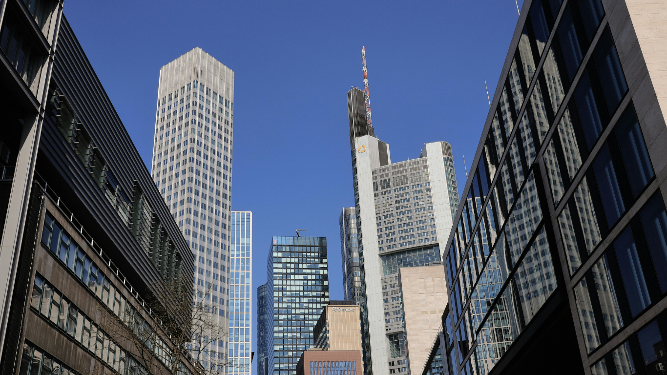 Looking down the street at a big city skyline against a blue sky.